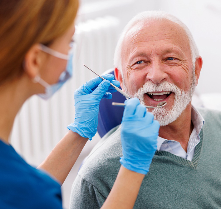 Senior man in gray sweater smiling during dental checkup
